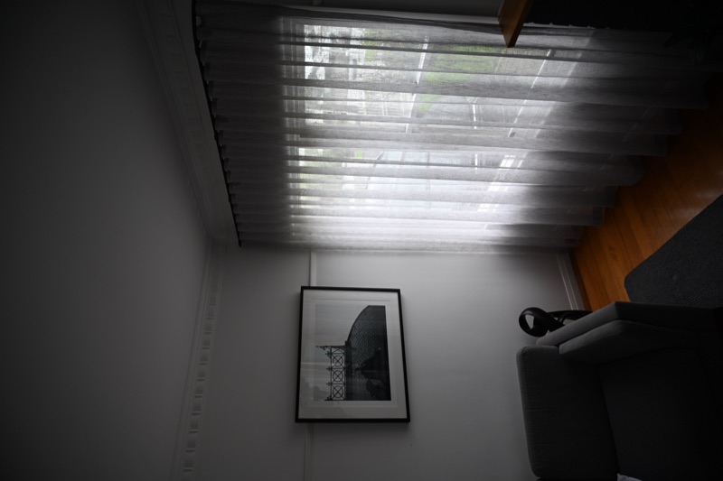 Floor-to-ceiling S-fold sheer curtains on a black track in a sitting room corner, softly filtering natural daylight