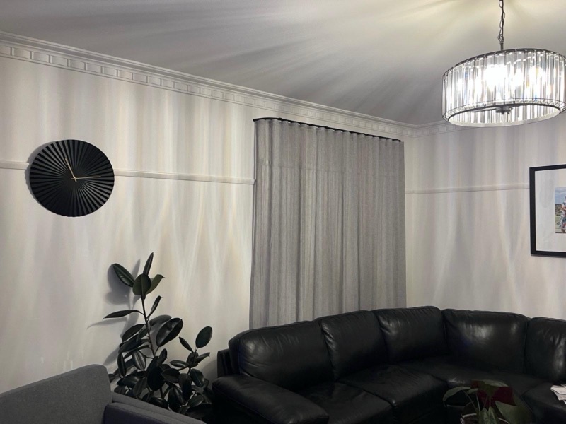White wave-fold sheers on a black track paired with a white roller blind in an elegant living room