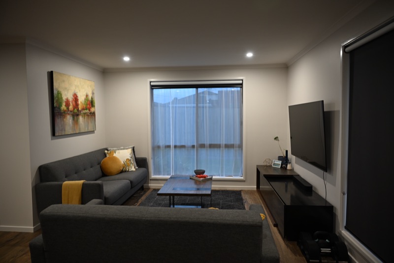 Sheer curtains layered with a charcoal roller blind on black tracks in a modern living room