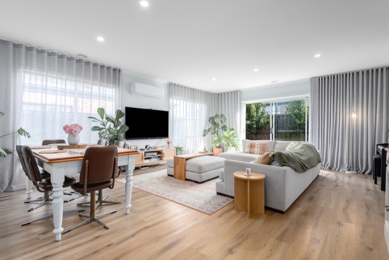 Open-plan living and dining room with floor-to-ceiling wave-fold sheers across multiple windows and a sliding door in light grey fabric